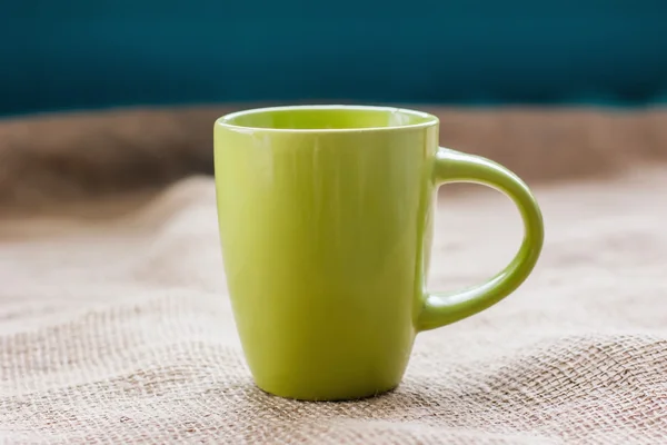 Taza verde en la mesa por la ventana en tela de saco aislado, con —  Fotos de Stock