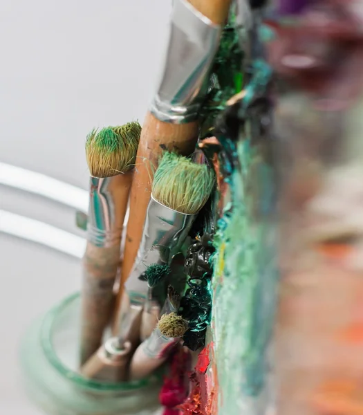 Konstnärens palett med oljefärger och borstar som används för att måla en — Stockfoto