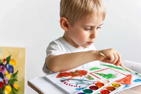 Happy cheerful child draws paints in an album, using a variety o — Stock Photo, Image