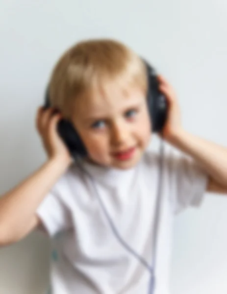 Счастливый веселый мальчик с наушниками, слушающий музыку на белом — стоковое фото