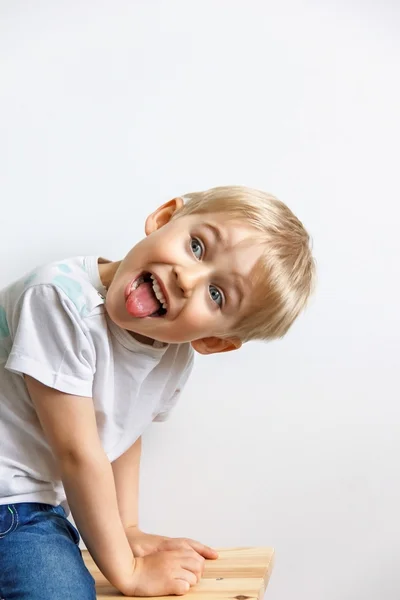 Anak kecil menggoda, menunjukkan lidah dan membuat wajah, pada ba putih — Stok Foto