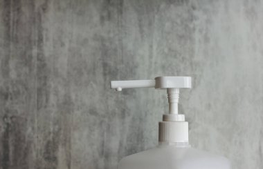 Bir çiçeğin ön planında gri bir arka planda sprey beyazı var. Kozmetik konsepti. Kozmetik konteynırlar. Dezenfektan için konteynır. Sprey..