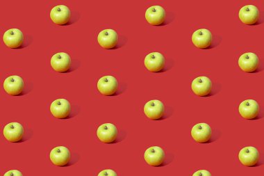 Kırmızı arka planda taze yeşil elmaların renkli meyve deseni. 