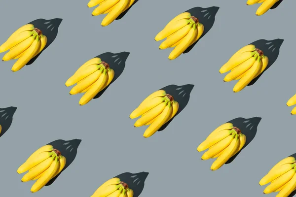 Bright pattern of yellow bananas on a gray background fashionable colors of 2021. Fruit patterns.