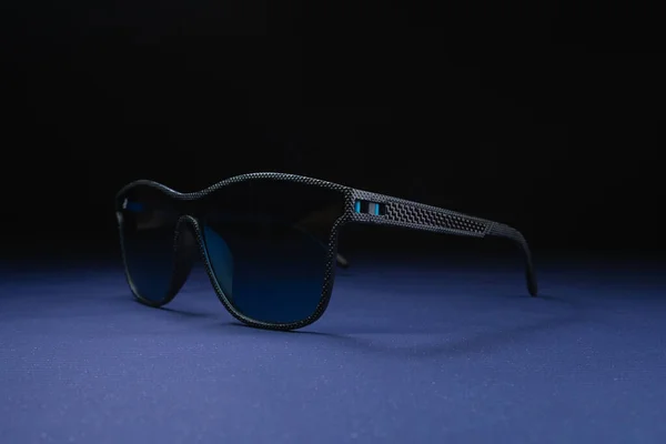 Gafas de sol con cristal azul y marco negro sobre fondo negro y púrpura. Plantilla para redes sociales, sitio web — Foto de Stock