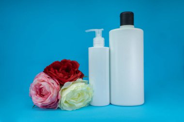 Mavi arkaplandaki spa kozmetik ürünlerinin şablonunu güllerle kapatın. Minimum konsept. Sunum için sunum cilt ürünleri