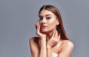 Temiz ciltli güzel bir genç kadın. Doğal çıplak makyajlı bir güzellik modeli. Spa, cilt bakımı ve sağlık. Kapat, gri arkaplan, telif alanı.