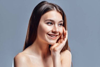 Temiz ciltli güzel bir genç kadın. Doğal çıplak makyajlı bir güzellik modeli. Spa, cilt bakımı ve sağlık. Kapat, gri arkaplan, telif alanı.