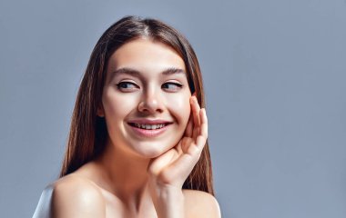 Temiz ciltli güzel bir genç kadın. Doğal çıplak makyajlı bir güzellik modeli. Spa, cilt bakımı ve sağlık. Kapat, gri arkaplan, telif alanı.