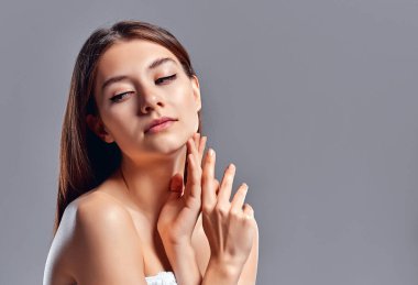 Temiz ciltli güzel bir genç kadın. Doğal çıplak makyajlı bir güzellik modeli. Spa, cilt bakımı ve sağlık. Kapat, gri arkaplan, telif alanı.