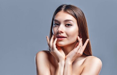 Temiz ciltli güzel bir genç kadın. Doğal çıplak makyajlı bir güzellik modeli. Spa, cilt bakımı ve sağlık. Kapat, gri arkaplan, telif alanı.