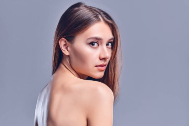 Temiz ciltli güzel bir genç kadın. Doğal çıplak makyajlı bir güzellik modeli. Spa, cilt bakımı ve sağlık. Kapat, gri arkaplan, telif alanı.