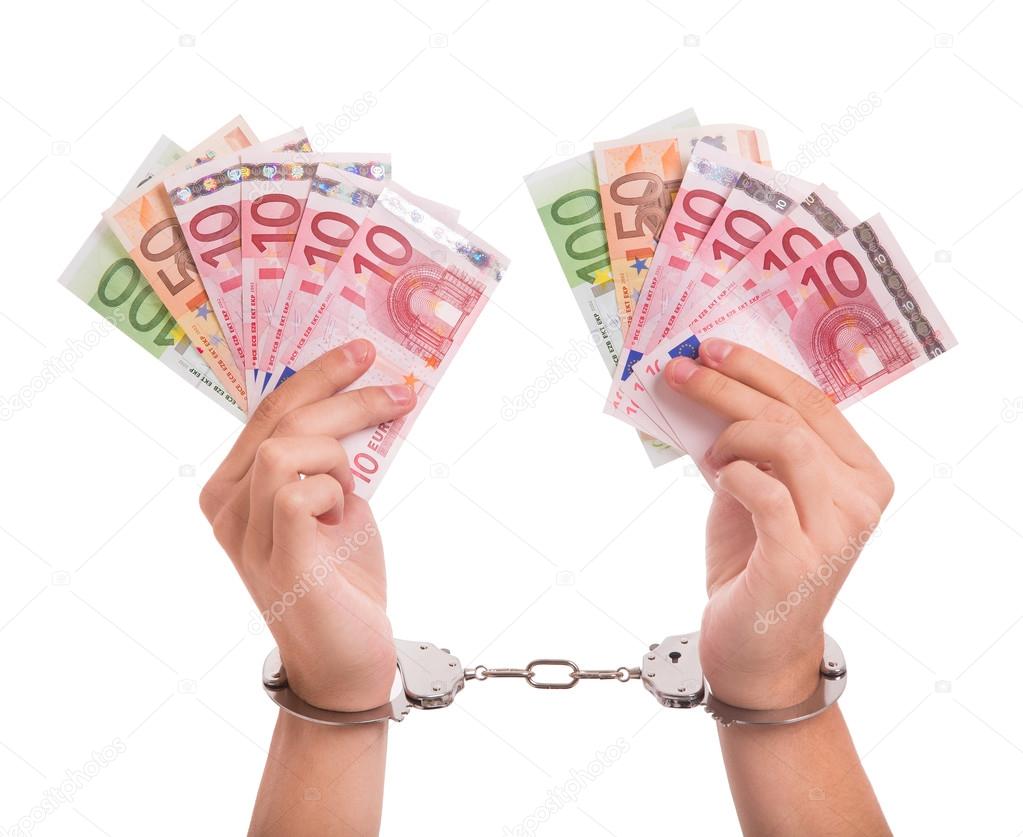 Counterfeit Money. Hands with handcuffs and Euro banknotes.