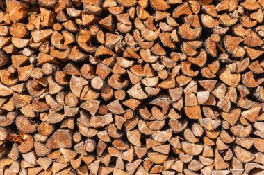Yığınla doğal odun yığını. Yakacak odundan yapılmış bir duvarın arka planı. Kışın ısınmaya hazırlanmak için geleneksel bir yöntem..