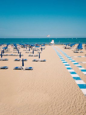 Büyük Britanya bayrağı taşıyan İtalyan tatil beldesi kumsalı. Güzel, geniş bir kumsalda mavi şemsiyeler..