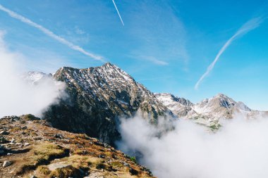 Avusturya 'nın Styria kentindeki Grosser Boesenstein manzarası, karla kaplı tepeler, kayalık arazi ve açık mavi gökyüzünün altından yükselen sis..