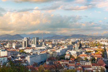 Slovenya 'nın Ljubljana kenti üzerinde sonbaharın sıcak renkleriyle çevrili nefes kesici bir panoramik manzara. Görüntü, tarihi merkezin, dolambaçlı sokakların ve uzak sokakların cazibesini yakalıyor.