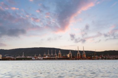 Slovenya 'nın Koper kentindeki sanayi limanı, gün batımında deniz kenarında renkli bulutlar ve turnalarla fotoğraflandı..