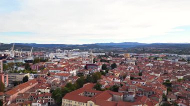 Koper, Slovenya 'nın insansız hava aracı panoraması, Adriyatik Denizi boyunca açık bir gökyüzünün altında eski kasaba, marina ve liman vinçlerini gösteriyor.