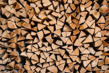 Yığınla doğal odun yığını. Yakacak odundan yapılmış bir duvarın arka planı. Kışın ısınmaya hazırlanmak için geleneksel bir yöntem..