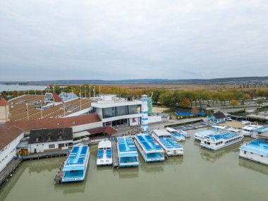 Moerbisch am See at Neusiedl in Burgenland, Avusturya. Tekneler ve ahşap rıhtımlar sığ göl boyunca uzanır geniş bulutlu gökyüzünün altında kamış manzarasıyla çevrili, huzurlu atmosferi yakalar.