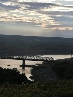 Akşam gökyüzünün arka planında nehrin üzerindeki köprü.