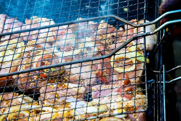 Pilhas marinadas de carne de porco em molho de soja e mostarda com anéis de cebola na grelha, envoltas em fumaça. — Fotografia de Stock