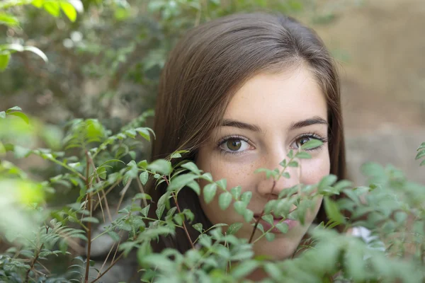 El rostro de una niña entre ramas de un árbol — Foto de Stock