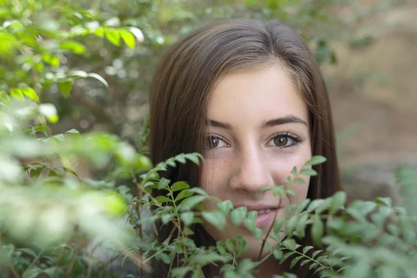 El rostro de una niña entre ramas de un árbol — Foto de Stock