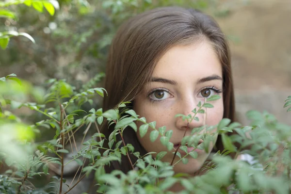 El rostro de una niña entre ramas de un árbol — Foto de Stock