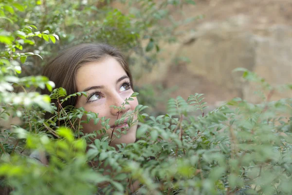 El rostro de una niña entre ramas de un árbol — Foto de Stock