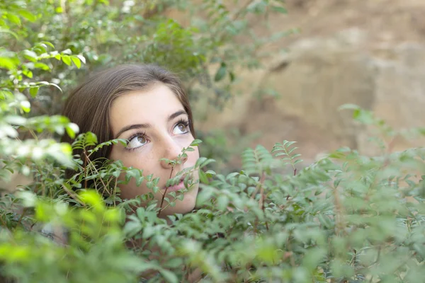 El rostro de una niña entre ramas de un árbol — Foto de Stock