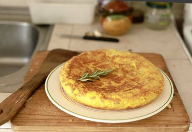 Beyaz bir tabakta, ahşap bir masanın arkasında ev yapımı İspanyol omleti..