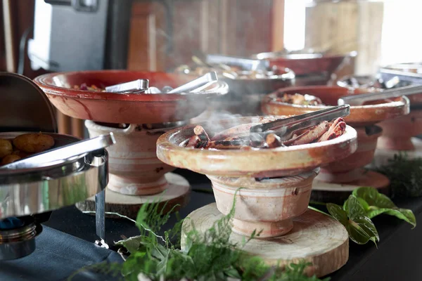 Cooked Belgian food placed in ceramic containers with a fire underneath to keep it warm.