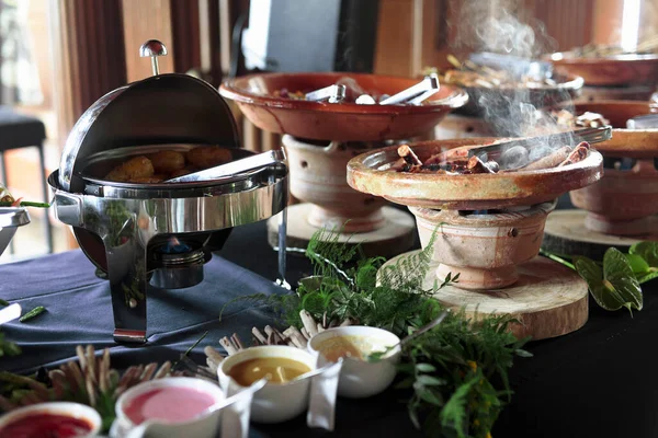 Cooked Belgian food placed in ceramic containers with a fire underneath to keep it warm.