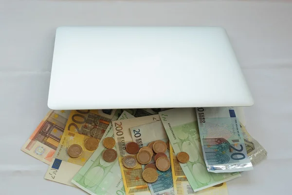Laptop mit Geld auf weißem Hintergrund — Stockbild Online gehandeltes Geld — Stockfoto