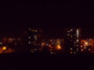 Blurred image of night houses with luminous windows.          