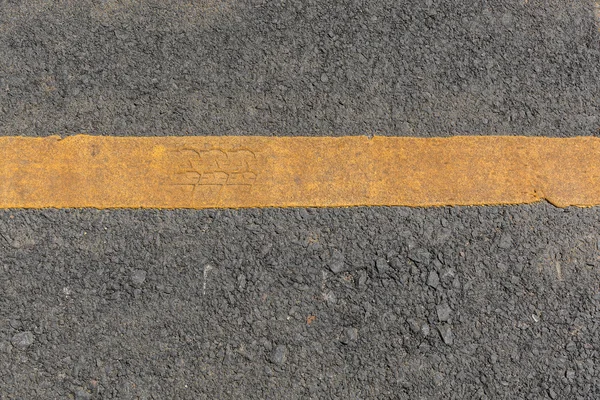 Żółta linia brudne na czarny asfalt drogowy tekstura — Zdjęcie stockowe
