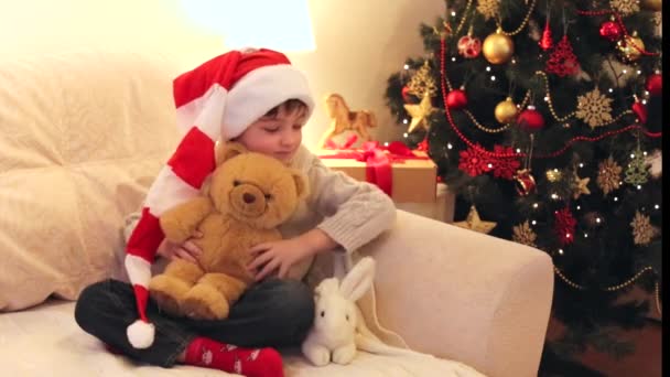 Menino brincando com brinquedos macios perto da árvore de Natal . — Vídeo de Stock