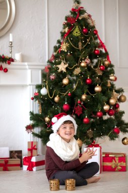 Bir Noel ağacı yanında oturan boy gülümseyerek