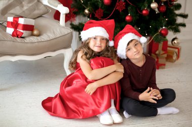 Noel Baba Noel ağacının altında hediyelerle oturan giyen çocuk