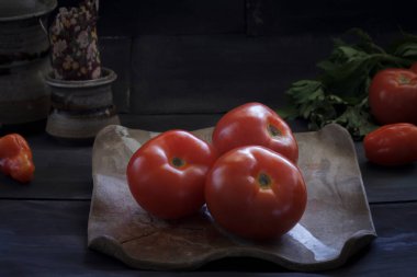 Koyu arkaplanda bir tabakta üç kırmızı domates. gastronomi kavramı