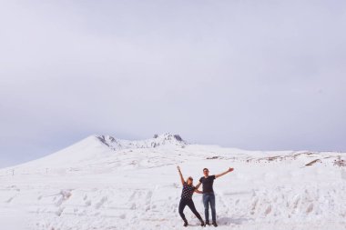 Sevgi dolu bir kız ve bir erkek, kışın bir dağın tepesinde tişörtle dolaşıyorlar.