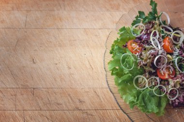 vegetable salad in a glass dish on a wooden cutting board with space for writing