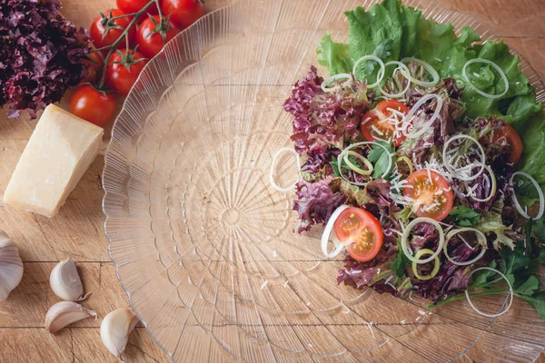 Vegetable salad in a glass dish on a wooden cutting board with space for writing — Stock Fotó