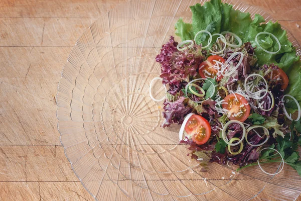 Salada vegetal em um prato de vidro em uma placa de corte de madeira com espaço para escrever — Fotografia de Stock