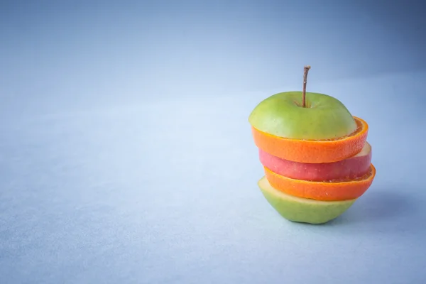Apple, orange cut into slices on a blue background — Stock Photo, Image