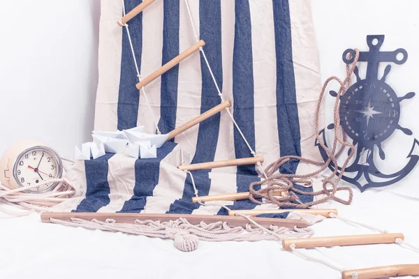 Ancla decorativa, barcos de papel y reloj marino sobre un fondo de rayas blancas y azules — Foto de Stock