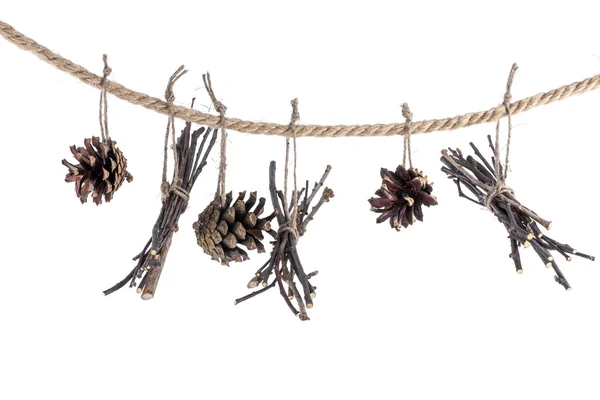 Guirnalda de conos y ramitas sobre una cuerda sobre un fondo blanco —  Fotos de Stock