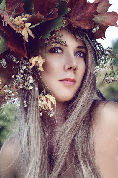 Cute girl on the nature in the autumn wreath of leaves